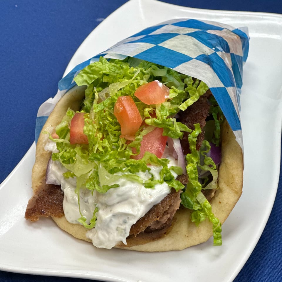 Opa Greek Restaurant's gyro, wrapped in blue and white checkered paper, filled with meat, lettuce, tomatoes, and tzatziki.